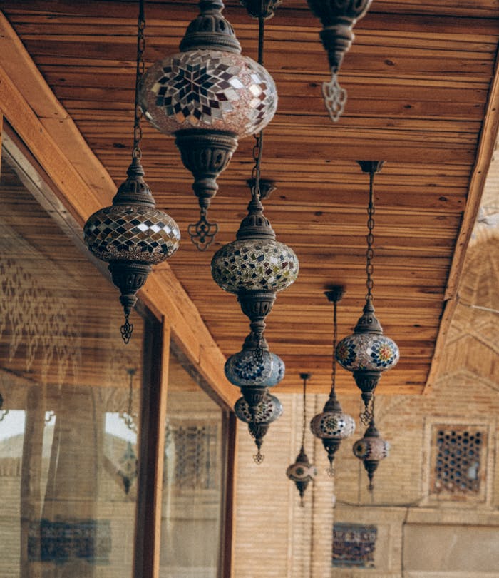 Traditional mosaic pendant lamps hanging from wooden ceiling indoors, enhancing elegant interior decor.