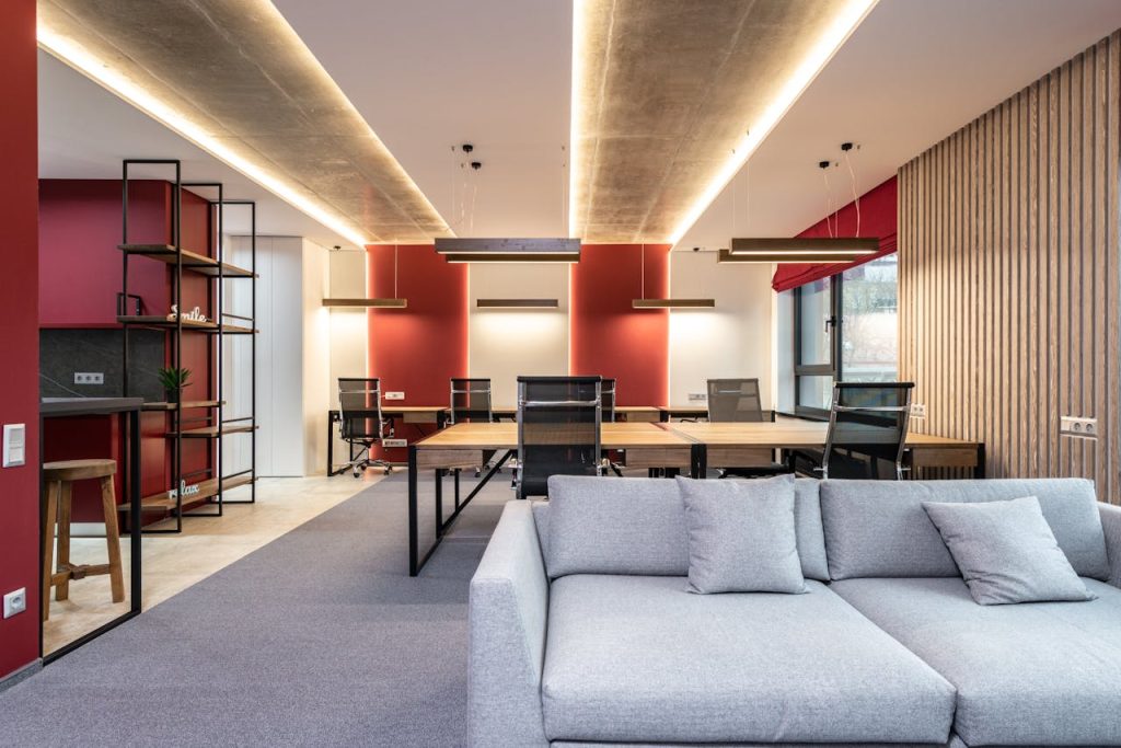 Spacious modern office featuring red accent walls, stylish furniture, and ample natural light.