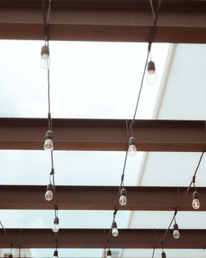 Minimalist ceiling design featuring beams and hanging light bulbs, perfect for architecture inspiration.