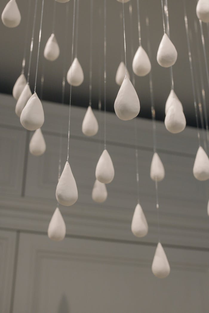 about-me-01 Close-up view of white raindrop-shaped decorations hanging from the ceiling indoors.